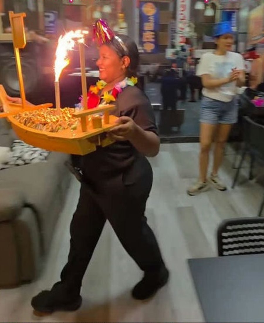 Mesero de Shitorii cargando un barco de sushi con una chispa encendida para un cumpleaños