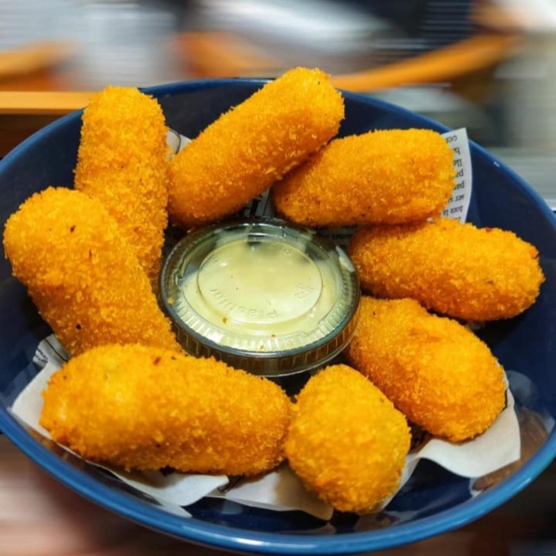 Croquetas doradas en plato azul con salsa tártara
