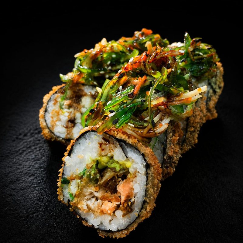 Sakura roll con masago y vegetales sobre tabla oscura